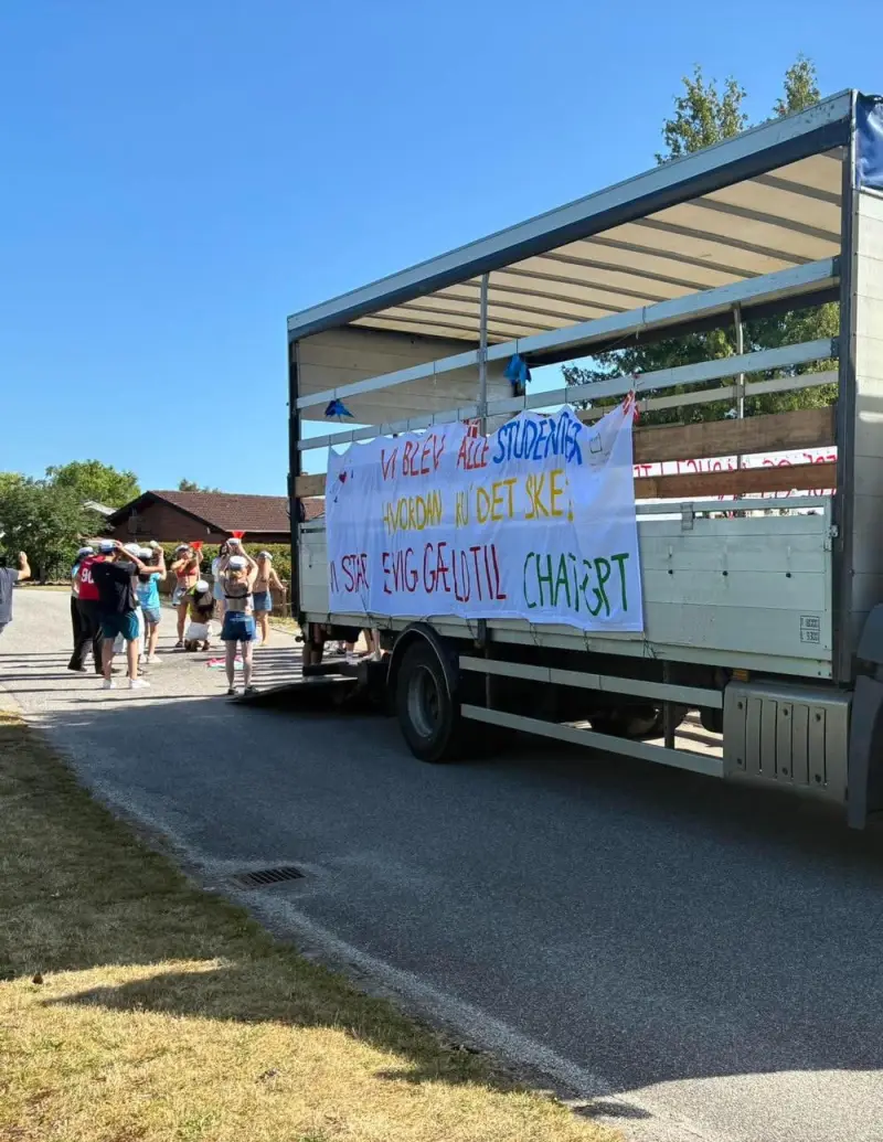 Studenter med huer ved den åbne vogn på en sommervej