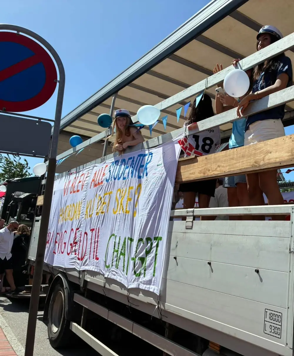 Studenter fejrer på den åbne studentervogn med banner og balloner